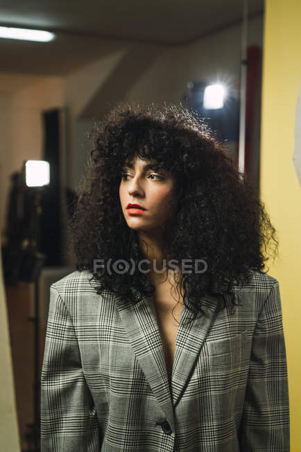 Curly woman in jacket posing at studio — Stock Photo