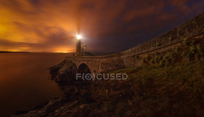 Scenic view to road and lighthouse at shore in evening dusk — Stock Photo