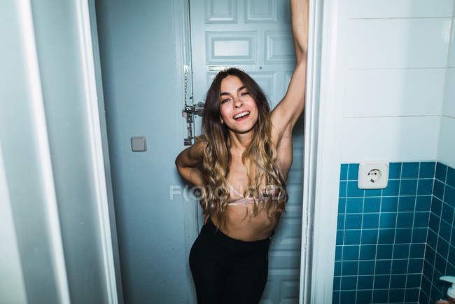 Attraktive Frau im BH lehnt an Badezimmertür. — Stockfoto