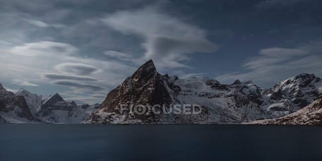 Panorama of lake amid snowy mountains in evening dusk — Stock Photo