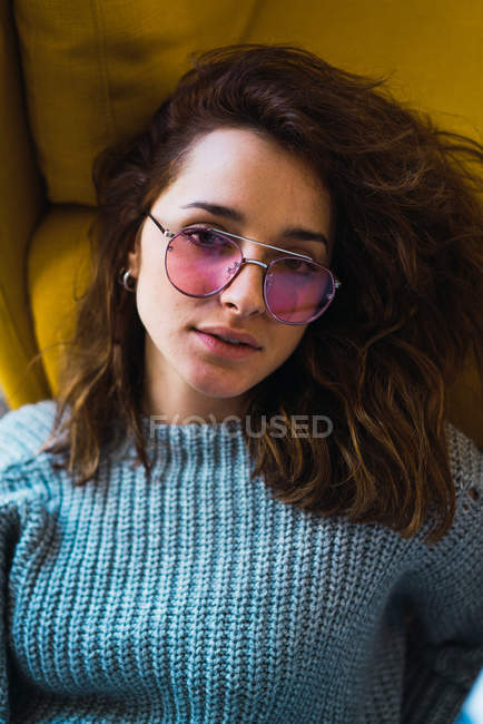 Портрет жінки в рожевих окулярах, що сидять на підлозі і дивляться на камеру — стокове фото