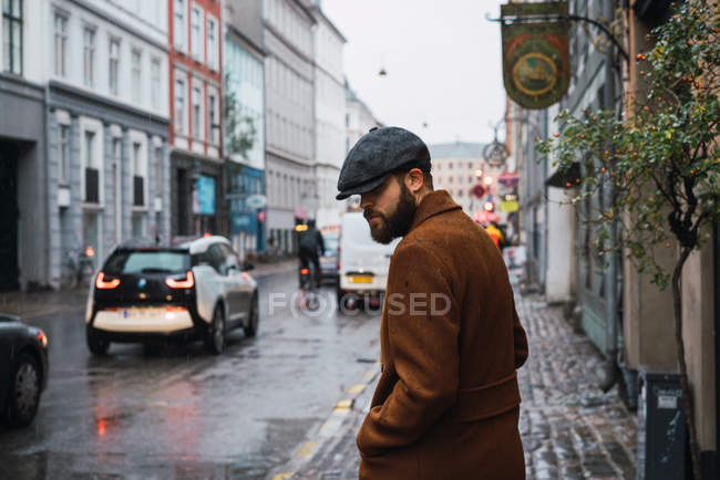 Seitenansicht eines bärtigen Mannes im Mantel, der auf der Straße spaziert — Stockfoto