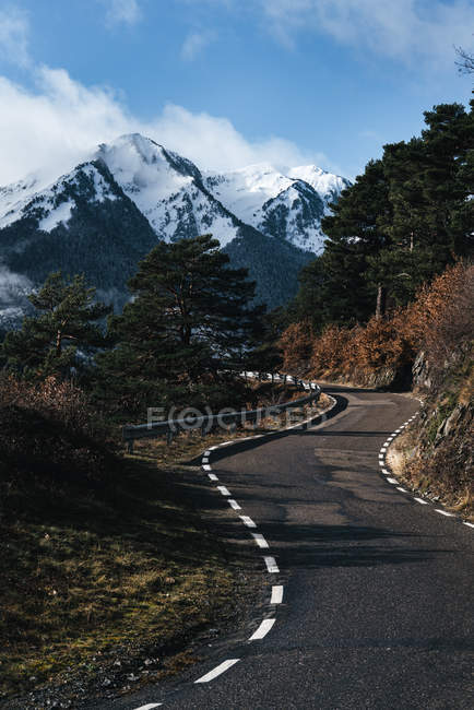 Vista al camino de asfalto que conduce a las altas montañas nevadas . - foto de stock