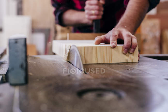 Cropped carpenter hands cutting piece of wood at workshop — Stock Photo