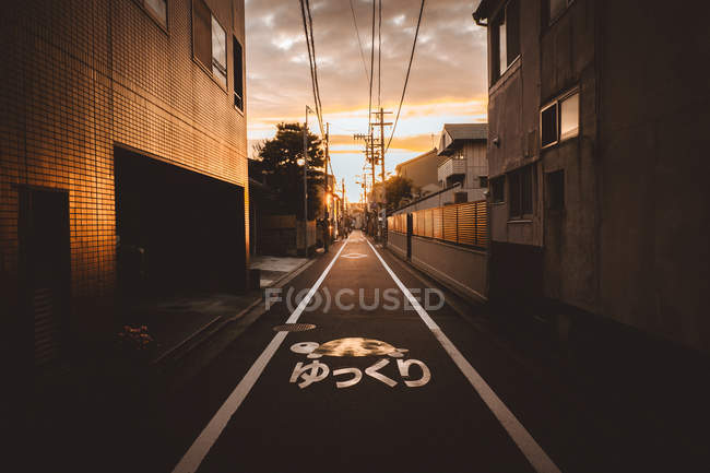 Perspective view to asphalt walkway in town in sunset lights. — Stock Photo