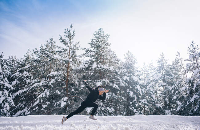 Seitenansicht einer sportlichen Frau, die schnell an Bäumen entlangläuft. — Stockfoto
