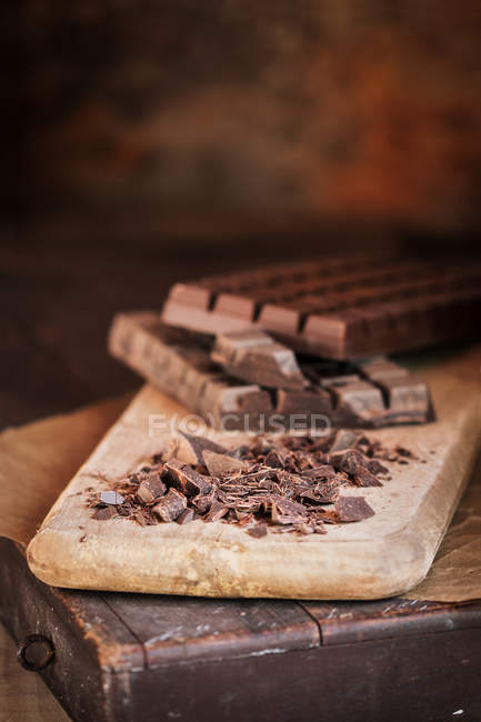 Gocce di cioccolato e barrette di cioccolato su tavola di legno — Foto stock