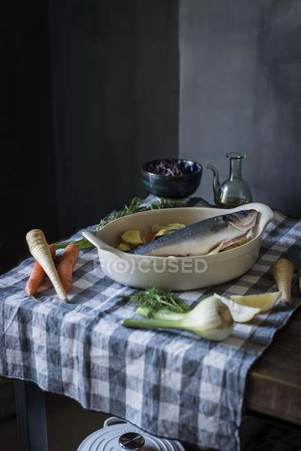 Still life of table with raw sea bass prepared for being cooked — Stock Photo