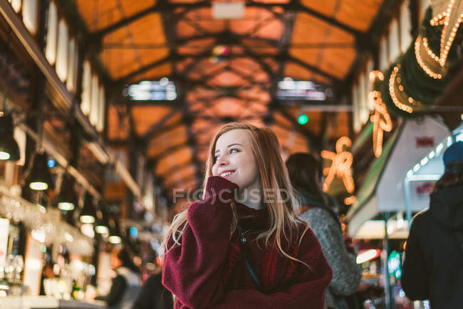 Fröhliche junge Frau steht auf Jahrmarkt an Kisten und schaut weg — Stockfoto