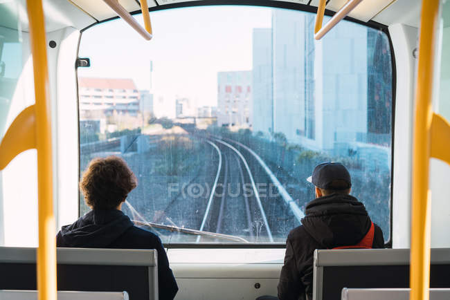 Vista posteriore di due uomini irriconoscibili che viaggiano sul treno della città . — Foto stock