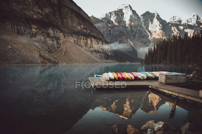 Row of boats on pier at calm mountain lake. — Stock Photo