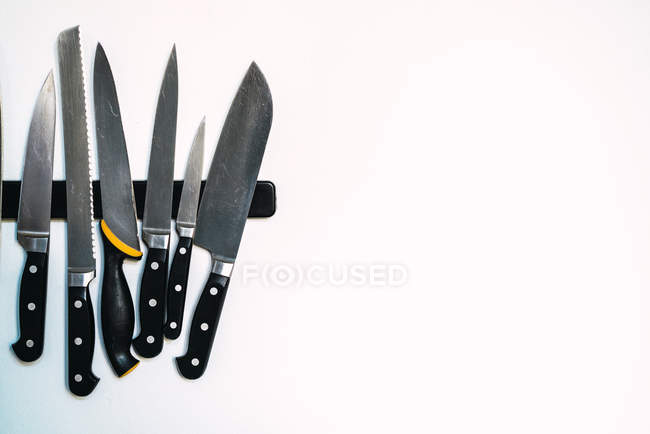 Magnet hanger with kitchen knives assortment on white wall. — Stock Photo