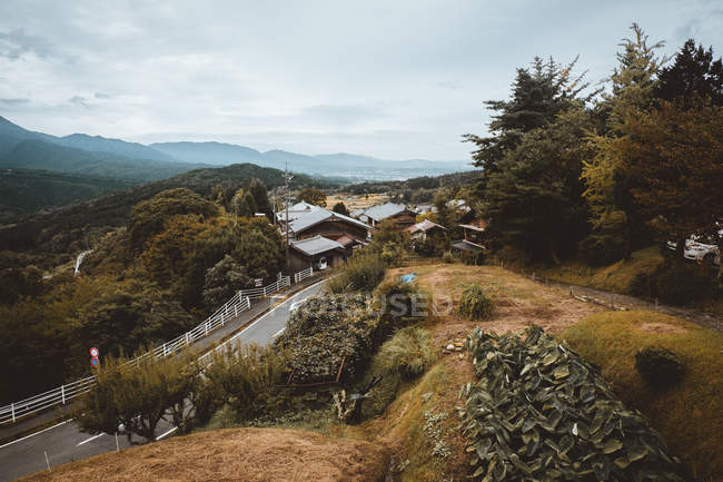 Сільська дорога орендує село в зелених лісових пагорбах — стокове фото