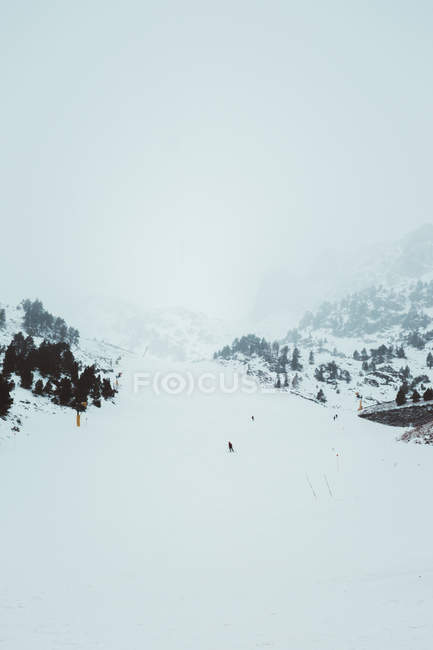 Vue lointaine des touristes qui font du snowboard dans les montagnes enneigées — Photo de stock