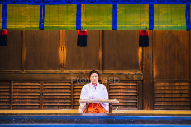 Donna asiatica in abiti tradizionali in posa presso edificio in legno. — Foto stock
