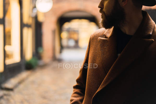 Урожай бородатий чоловік в пальто, що спирається на стіну — стокове фото