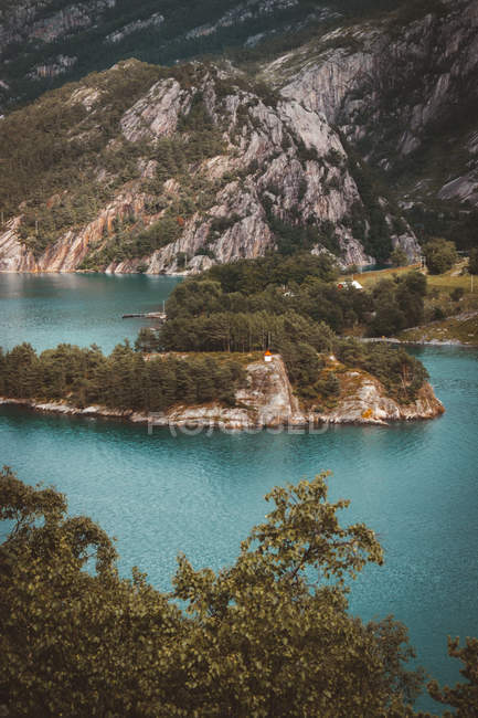 Small island on turquoise lake in green mountains landscape. — Stock Photo