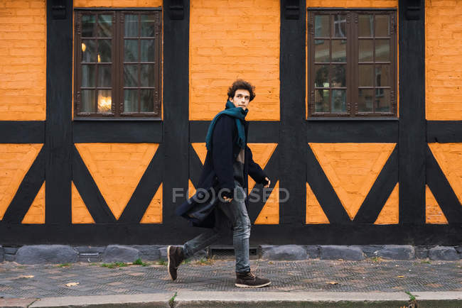 Side view of man in coat walking fast on city street and looking away — Stock Photo