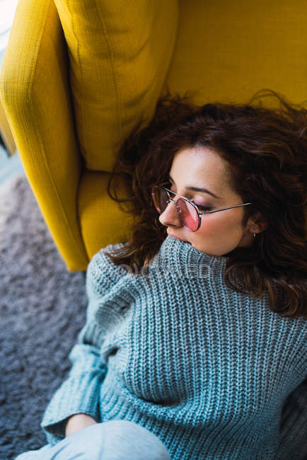 Жінка в окулярах сидить на підлозі і кусає светр коміром — стокове фото