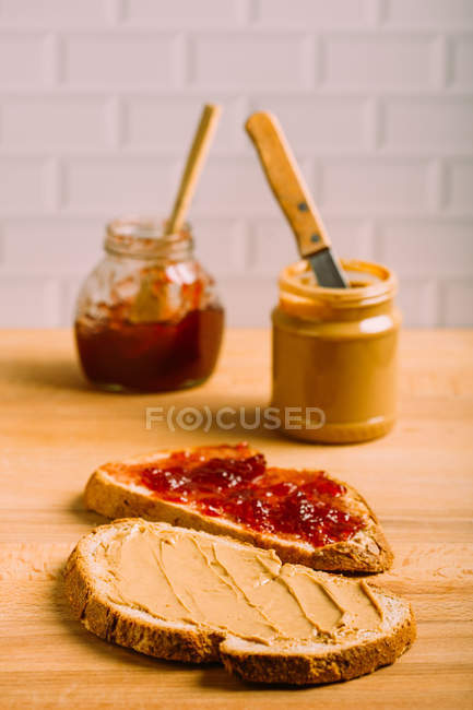 Крупним планом дивитися арахісове масло і желе бутерброди на фоні банок — стокове фото