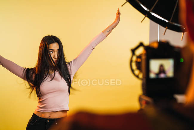 Over shoulder view of photographer taking shots of pretty woman on yellow background. — Stock Photo