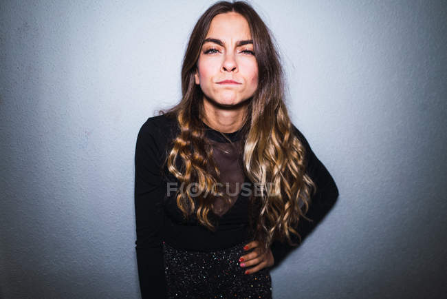 Portrait of expressive suspicious woman standing on background of white wall. — Stock Photo