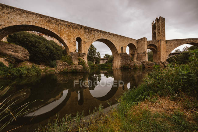 Exterior view of medieval bridge reflecting in river — Stock Photo