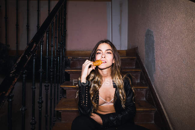Приваблива жінка сидить на сходах і кусає печиво — стокове фото