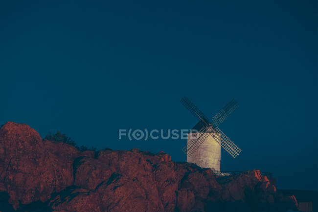 Ветряная мельница белого цвета, расположенная на вершине горы ночью . — стоковое фото