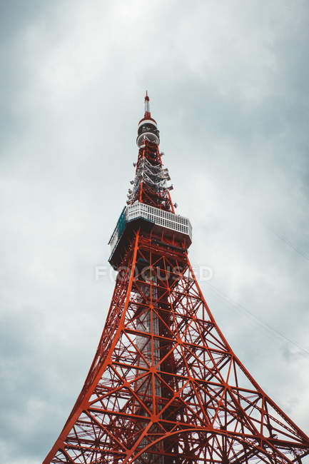 From below big red telecommunication tower on background of cloudy sky. — Stock Photo