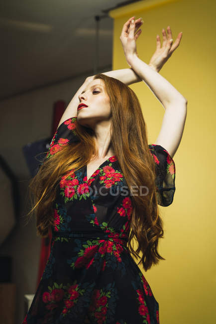 Donna rossa che balla con le braccia alzate in studio — Foto stock