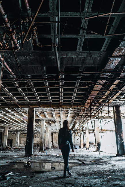 Vista posteriore della donna in piedi in camera abbandonata intemperie
. — Foto stock