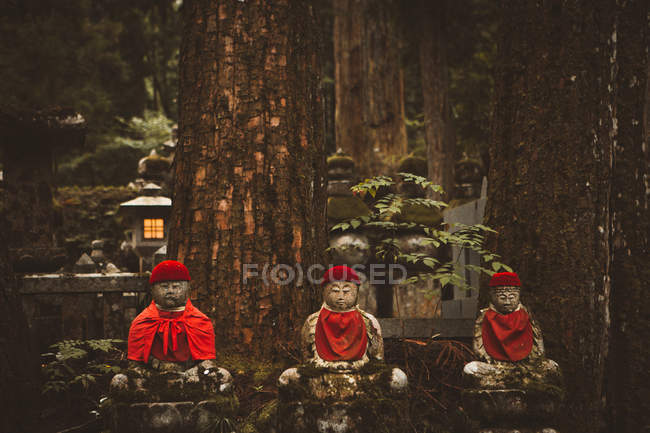 Tres pequeñas estatuas religiosas asiáticas en el bosque . - foto de stock