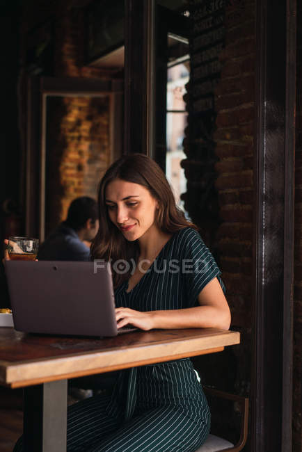 Donna allegra che naviga laptop in caffè — Foto stock
