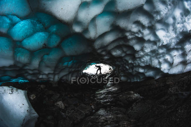 Silhouette of person posing in end of ice cave with textured beautiful ceiling. — Stock Photo