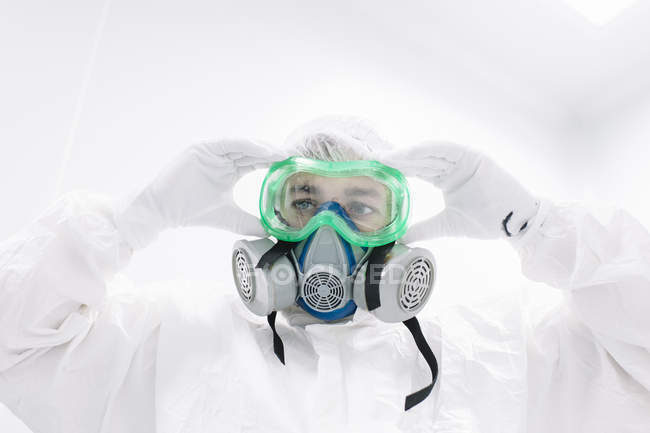 Retrato del científico poniéndose máscara protectora - foto de stock