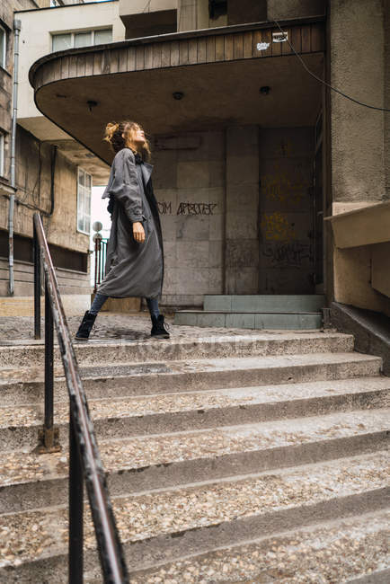 Menina na moda posando nas escadas e olhando para longe — Fotografia de Stock