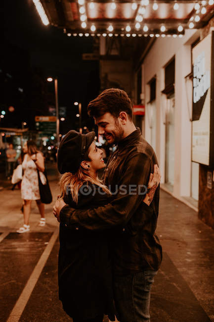 Улыбающаяся пара обнимается на вечерней улице — стоковое фото