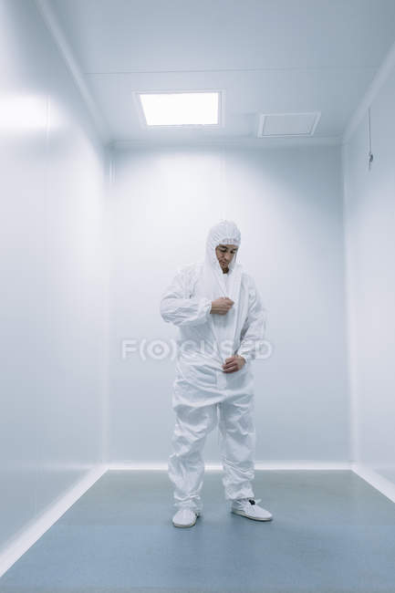Дослідник людина надягає білий костюм перед дослідженням в лабораторії . — стокове фото