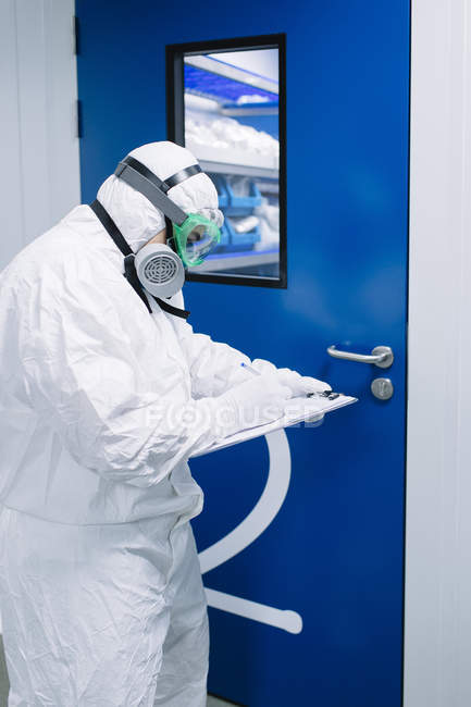 Researcher in white costume writing on tablet at laboratory. — Stock Photo