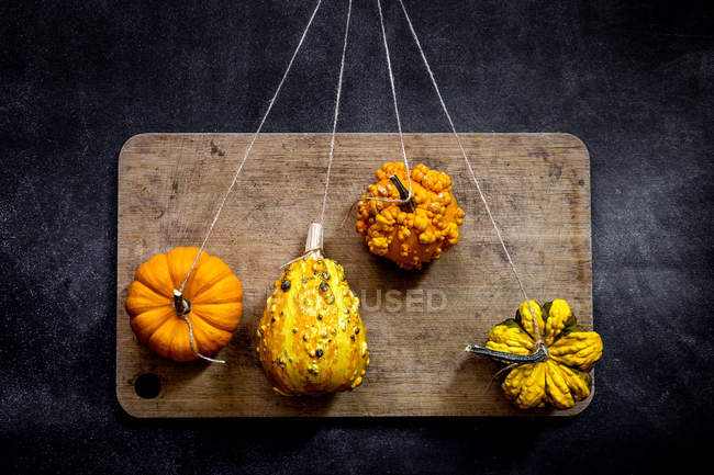 Arrangement of pumpkins on strings on cutting board — Stock Photo