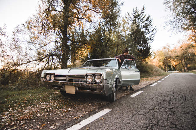 Молода людина стає vintage автомобіля на узбіччі дороги — стокове фото