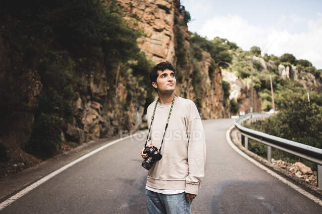 Homem com câmera andando em uma estrada rural — Fotografia de Stock