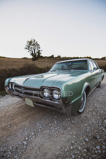Retro car standing on rural road near field with dry grass. — Stock Photo
