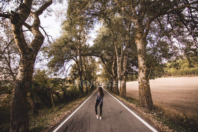 Donna che cammina sulla strada rurale e guarda indietro — Foto stock