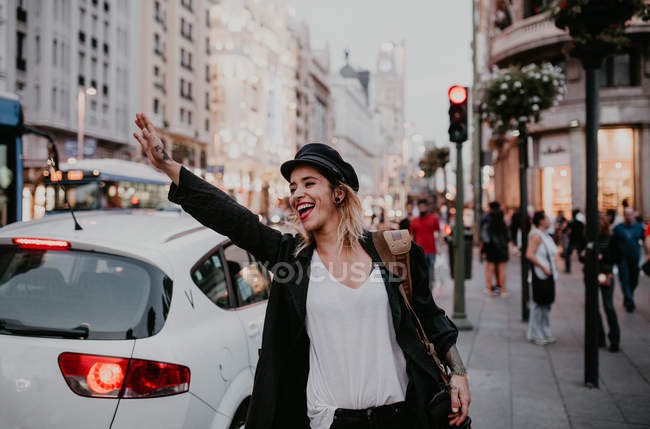 Femme gaie prenant un taxi dans la rue de la ville — Photo de stock
