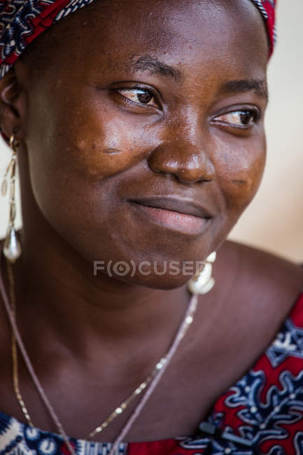 BENIN, AFRIQUE - 31 AOÛT 2017 : Portrait d'une femme noire souriante en vêtements ethniques détournant les yeux . — Photo de stock