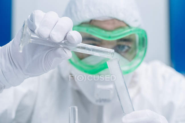 Fermer la main du scientifique versant le réactif dans des flacons pendant l'expérience — Photo de stock