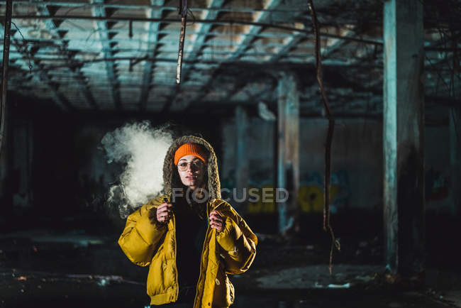 Giovane donna in giacca gialla in edificio abbandonato — Foto stock