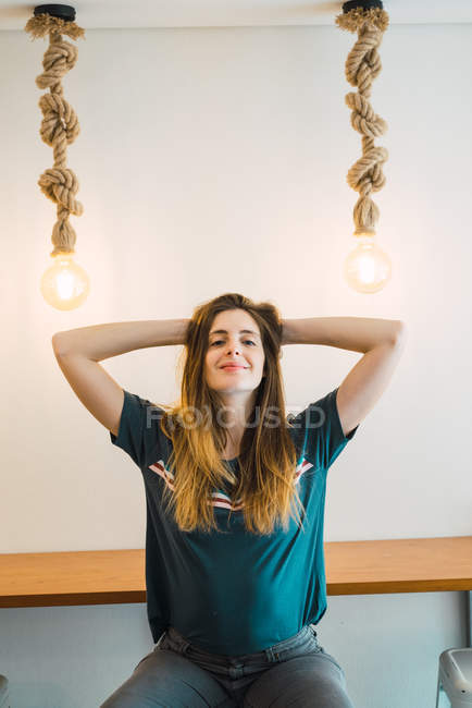 Young brunette posing with hands behind head and looking at camera. — Stock Photo